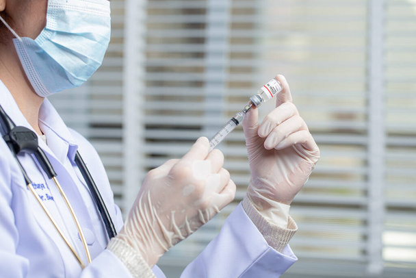 Ασιάτης ιατρός, νοσοκόμος με μάσκα, κρατήστε τη σύριγγα με εμβόλιο. Covid-19, νόσος του Coronavirus, έννοια των εργαζομένων στον τομέα της υγείας. - Φωτογραφία, εικόνα