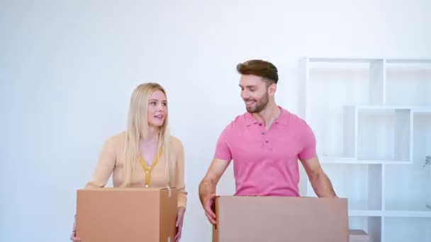 Úžasné novomanželé blondýny a chlap nosit velké lepenkové krabice - Záběry, video