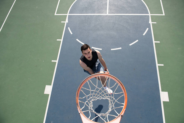 Young sportsman playing basketball on basketball court outdoor. - Valokuva, kuva