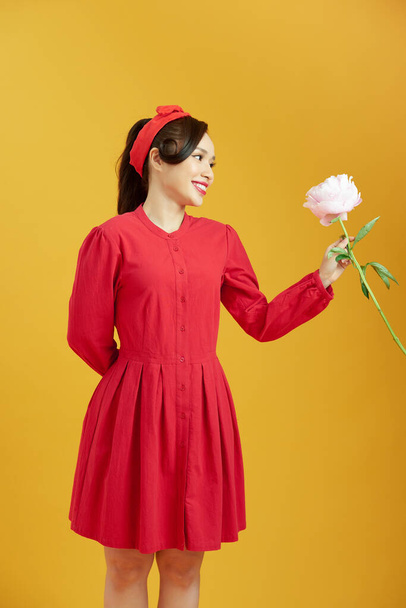alegre encantadora joven mujer recibiendo rosa peonía de su novio sobre amarillo fondo - Foto, Imagen