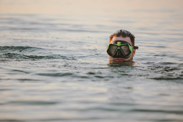 людина з маскою снорклінгу у воді на заході сонця крупним планом
 - Фото, зображення