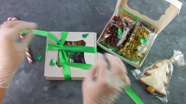 Chica envuelve caja de regalo con frutos secos conjunto envuelto individualmente. Alimentación saludable. Celebración navideña vacaciones preparando eco snack natural en manos femeninas.Consumo consciente dulces caseros - Metraje, vídeo