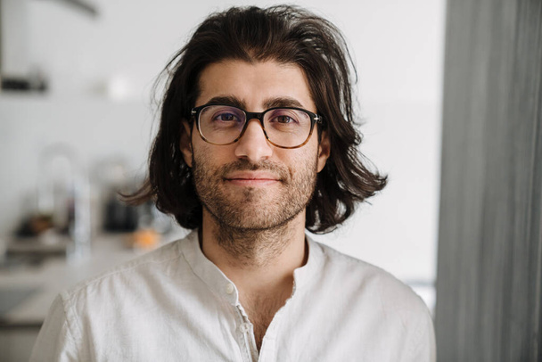 Close up of a smiling mid aged brunette turkish man face wearing white shirt glasses indoors looking at camera - Фото, зображення