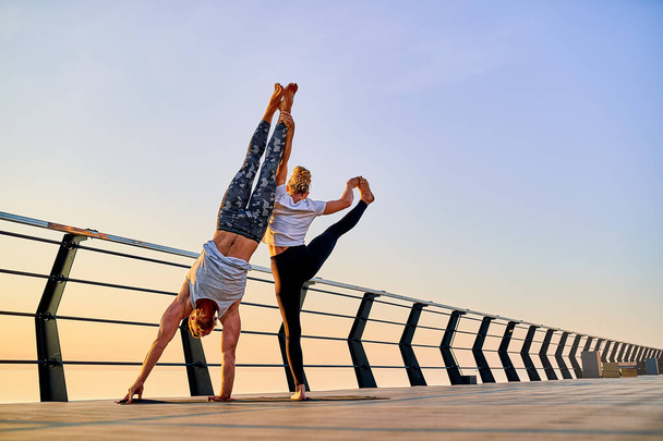 Couple doing practicing yoga together on nature outdoors . Morning exercises at the sunrise. - Foto, Imagem