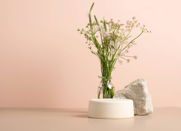 Modern abstract podium wooden geometric shapes stone green fresh field plants grass pastel pink background - Fotó, kép