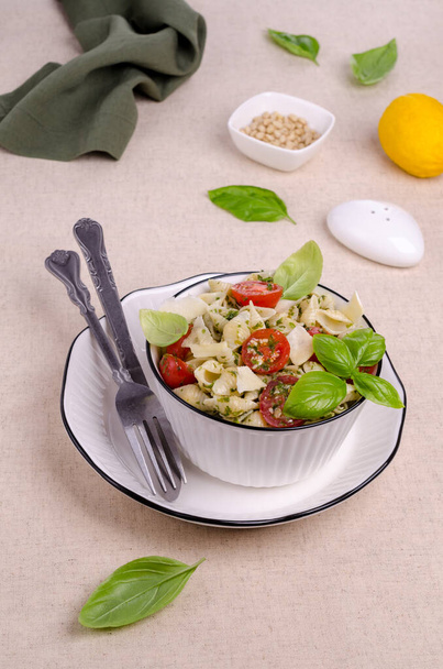 Shell pasta with tomatoes and pesto in a ceramic dish on a textile background. Selective focus - Фото, изображение