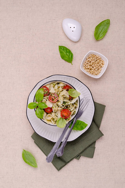 Shell pasta with tomatoes and pesto in a ceramic dish on a textile background. Selective focus - Φωτογραφία, εικόνα