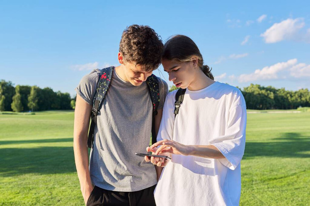 Teenagers friends talking looking at smartphone screen - Foto, afbeelding