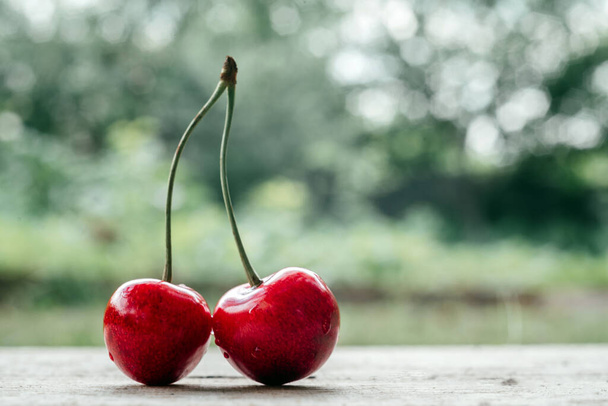 Lahodné sladké třešně zblízka na dřevěném stole s letní zelené pozadí bokeh, letní ovoce vysoké na vitamíny a antioxidanty - Fotografie, Obrázek