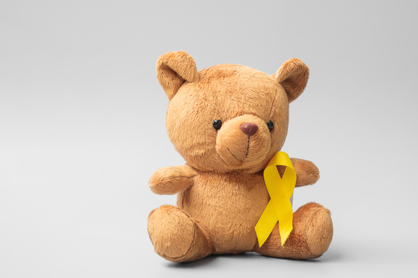 国際小児がん啓発月間、子供たちが住む子供たちをサポートするための金色のリボンでおもちゃ。医療と世界のがんの日のコンセプト - 写真・画像