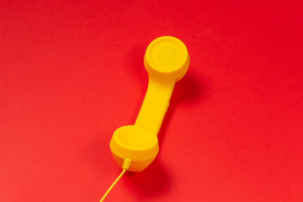 Yellow handset on red background.  - Zdjęcie, obraz