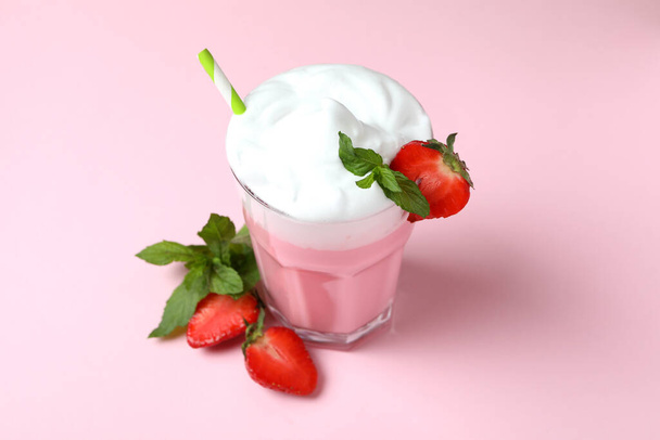 Glass of strawberry milkshake and ingredients on pink background - Fotó, kép
