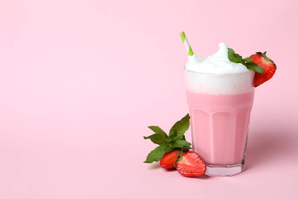Стакан клубничного молочного коктейля и ингредиенты на розовом фоне - Фото, изображение