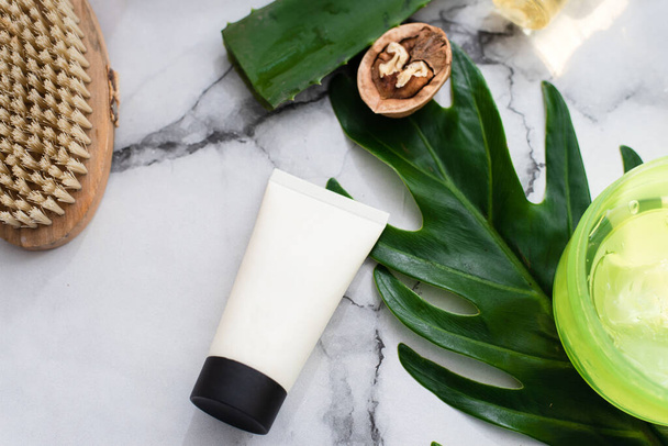 Crema facial sobre fondo de hoja de palma, ingredientes naturales y fondo de mármol - Foto, Imagen