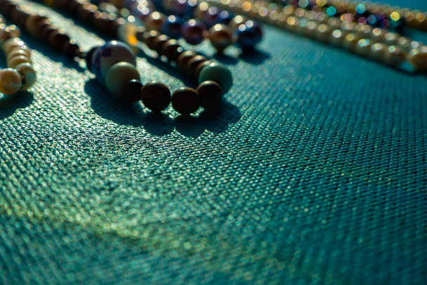 Haufen farbiger, heller Schmuckperlen auf blauem Hintergrund. Verschiedene Edelsteine Perlenkette. Juwelenkette moderne Mode Muster oder Textur. Raum für Text. Hochwertiges Foto - Foto, Bild
