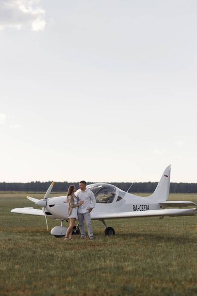 Smiling people and a private plane in the background. A couple of lovers, in the cockpit on their own plane. - Foto, imagen