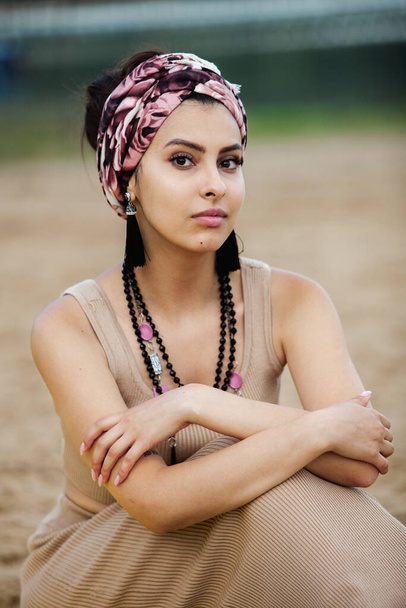 Портрет красивой индийской девушки в шарфе. Молодая женщина в стиле хиппи носит украшения ручной работы - Фото, изображение