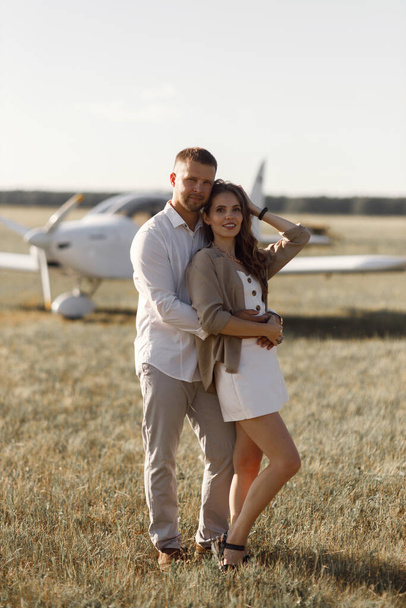 Smiling people and a private plane in the background. A couple of lovers, in the cockpit on their own plane. - Фото, изображение