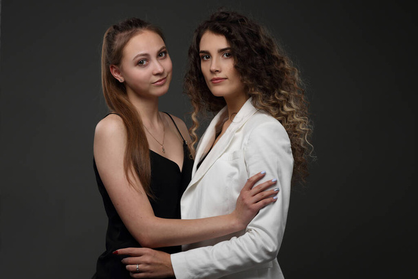 Studio group portrait of two girls on a dark background - 写真・画像