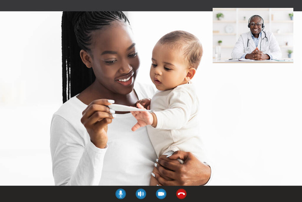 Afrikkalainen amerikkalainen äiti, jolla on videopuhelu lastenlääkärin kanssa lämpömittarin avulla - Valokuva, kuva