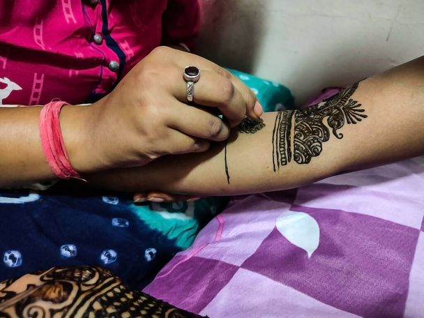 Foto de stock del artista de henna aplicando o dibujo diseño de henna en la mano de la novia con cono de tubería para la ceremonia tradicional mehnadi en la boda india en Kolhapur maharashtra India. - Foto, Imagen