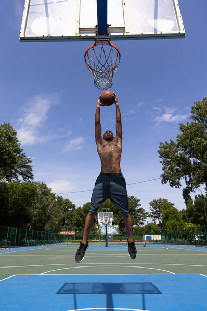 Strong muscular african-american male basketball player training at street public stadium, sport court or palyground outdoors. Concept of healthy active lifestyle, motion, hobby. - Fotoğraf, Görsel