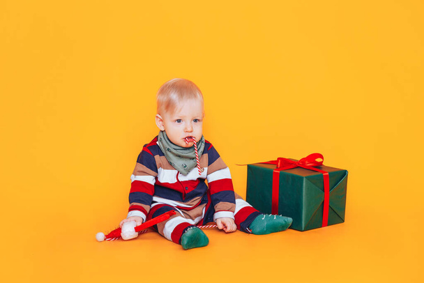 Pieni poika karkkia ja lahja edessä keltainen tausta - Valokuva, kuva