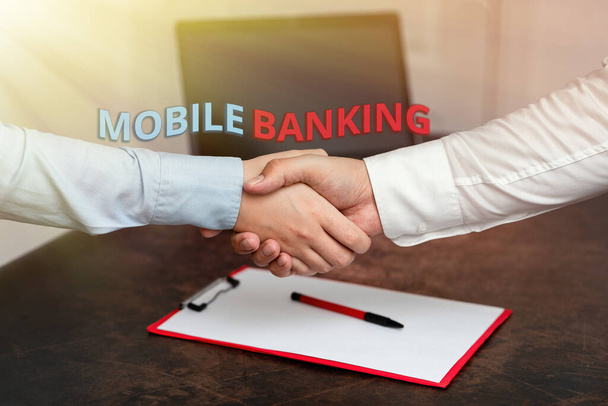 Käsiala teksti Mobile Banking. Liiketoiminta lähestymistapa luoda finanssitransaktioiden avulla älypuhelimen Kaksi Professional Hyvin pukeutunut Corporate Businessmen kädenpuristus sisätiloissa - Valokuva, kuva