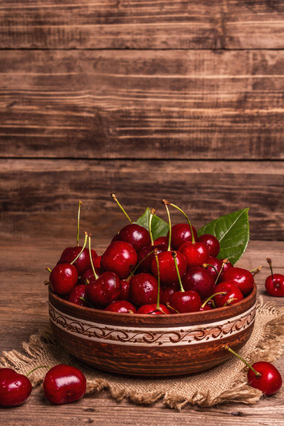 Cerezas dulces frescas maduras en un tazón con gotitas de agua. Fondo de madera rústico oscuro, espacio para copiar - Foto, Imagen