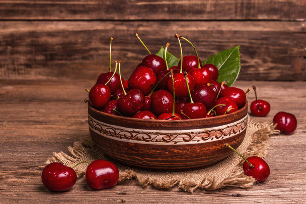 Fresh ripe sweet cherries in a bowl with droplets of water. Dark rustic wooden background, copy space - Photo, Image