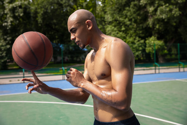 Strong muscular african-american male basketball player training at street public stadium, sport court or palyground outdoors. Summer sport games. - Zdjęcie, obraz