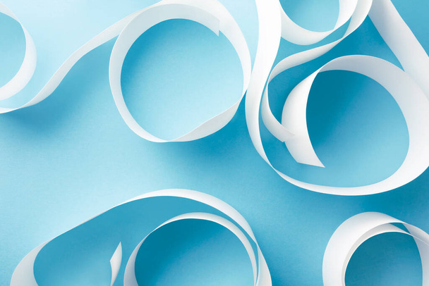 Close-up of white paper curls on light blue background - Foto, imagen