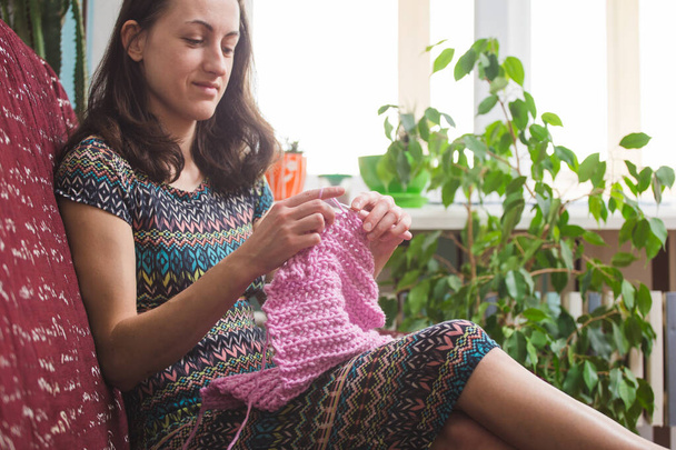 Kobieta robi na drutach. domowe wełniane ubrania. w wolnym czasie, dziewczyna jest zaangażowana w hobby. - Zdjęcie, obraz