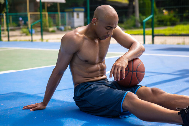 One african-american male basketball player playing at street public stadium, sport court or palyground outdoors. Concept of healthy active lifestyle, motion, hobby. - Fotografie, Obrázek