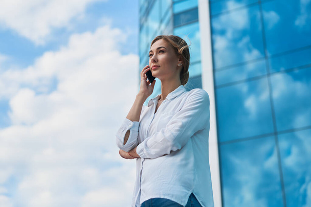 Businesswoman successful woman business person standing outdoor corporate building exterior cell phone Pensive elegance cute caucasian professional business woman middle age dreaming with mobile phone - Photo, Image