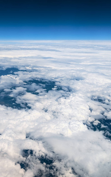 Blick aus dem Flugzeug auf den blauen Himmel und die weißen Wolken, Nahaufnahme von der Seite. - Foto, Bild