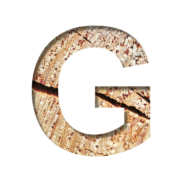 Wood cut font. The letter G cut out of paper on the background of a cut of a tree with cracks and shavings. Set of decorative natural alphabet fonts. - Фото, изображение