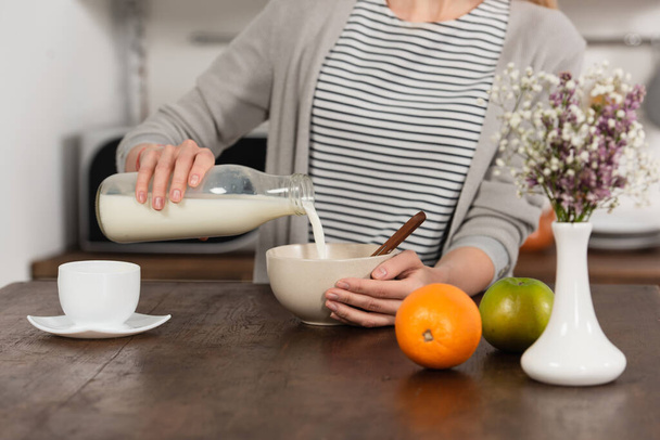 partial view of woman pouring milk in bowl - Photo, Image