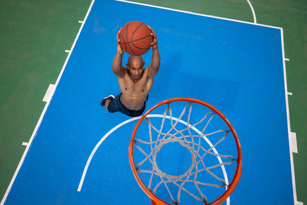 High angle view of young man, male basketball player playing basketball at street public stadium, sport court or palyground outdoors. Summer sport games. - Foto, Imagem