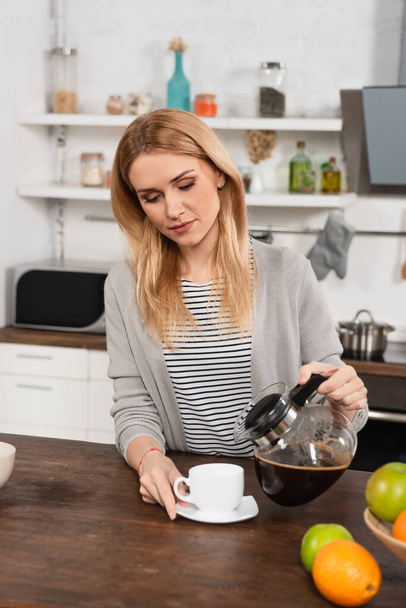 blonde woman pouring coffee in cup from pot - Foto, imagen