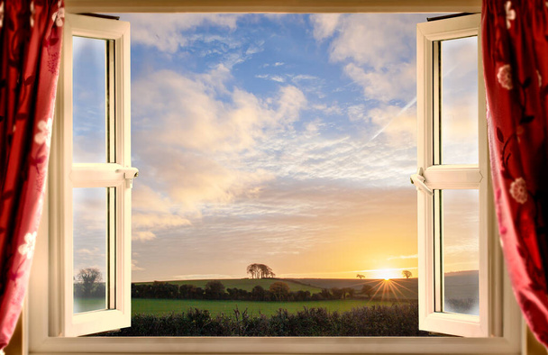 Atemberaubender Blick aus dem offenen Fenster auf eine ländliche Landschaft bei Sonnenaufgang im Sommer.  - Foto, Bild