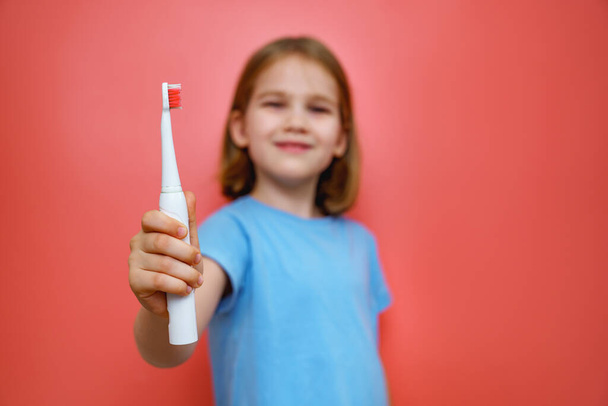 focus on the toothbrush. girl in a blue on a pink background with a toothbrush.  - Fotó, kép
