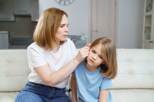 a girl complains of pain in ear and her mother examines it. childrens diseases. - Фото, зображення