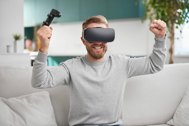 Cheerful gamer with VR headset playing videogame - Foto, imagen