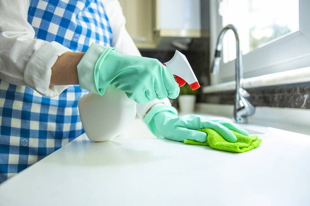 Unrecognizable woman cleaning kitchen counter with rag and spray cleaner - Foto, immagini