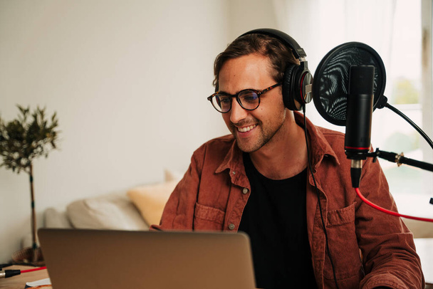 Caucasian male freelance podcaster wearing headphones listening to internet subscribers  - Foto, immagini