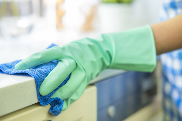 Close-up of a hand in a protective glove holding a rag. Cleaning the kitchen - 写真・画像