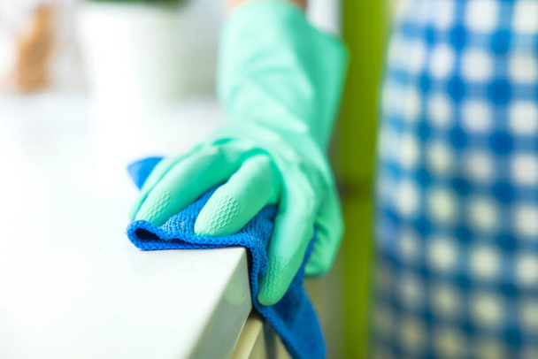 Close-up of a hand in a protective glove holding a rag. Cleaning the kitchen - Foto, Imagen