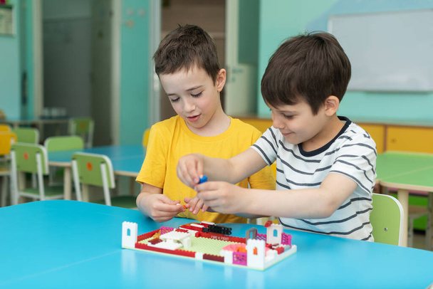 two boys are enthusiastically playing Lego in the kindergarten. Leisure in kindergarten - Photo, Image
