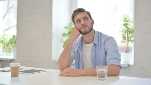 Jonge creatieve man zit in het moderne kantoor denken  - Video